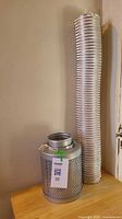 Air filter canister next to full length of aluminum ducting