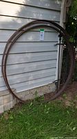 Two large rusted steel rims leaning against siding