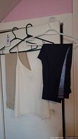 Full view of pants, leggings and camisole on hangers