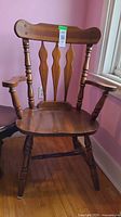 Front view of wooden captain’s dining armchair showing seat, arms, spindle legs and back slats
