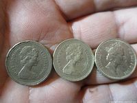 Obverse of three UK £1 coins showing Queen Elizabeth II effigy and dates 1983, 1984, 1985