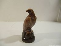 Front view of brown ceramic eagle miniature bottle on base