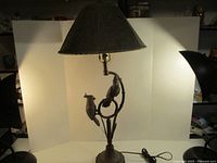 Full view of lamp with shade illuminated, birds visible, power cord shown