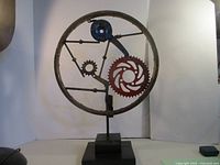 Front view of circular metal sculpture with gears and base