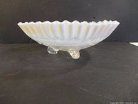 Side view showing ruffled rim, opalescent color gradient, and three scroll feet