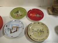 Four round plates with cocktail designs arranged on white surface