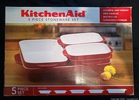 Front of sealed box showing KitchenAid 5-piece stoneware set, graphics of nested red and white bakers