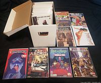 Short comic box filled with bagged comics and eight first-issue examples laid out in front.