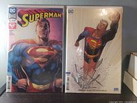 Front view of two bagged Superman #1 comics, standard and Variant B covers visible