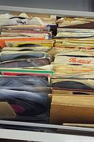 Drawer filled with rows of 7-inch 45 RPM records in various sleeves