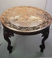 Full view of round carved rosewood table showing top and legs