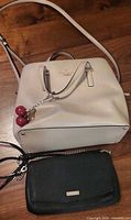 Cream Kate Spade satchel and black cross-body clutch overview