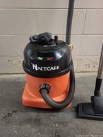 Front view of Nacecare canister vacuum showing hose connection and floor head