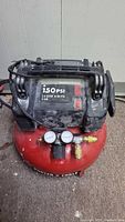 Full view of Porter-Cable red pancake air compressor with handle and hose wrap