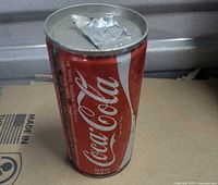 Front of red Coca-Cola steel can standing upright showing logo and wear