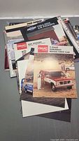 Stack of assorted GMC, Dodge and Chevy truck brochures on table