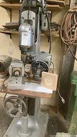 Full view of drill press with two motor attachments and mold on table