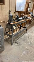Full view of lathe on metal and wood stand with motor, tailstock and tool rest visible