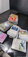 Stacks of Japanese Pokémon cards on table, showing card backs and fronts