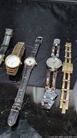 Close view left four watches (gold round, small leather, silver rhinestone, gold square)