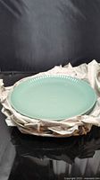 Stack of mint green stoneware plates with packing material