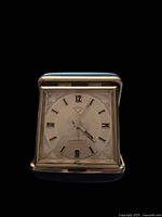 Front view of folded clock showing gold-tone dial and blue case edge