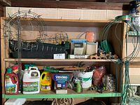 Shelf with multiple gardening items including wreath rings, seed trays and chemicals
