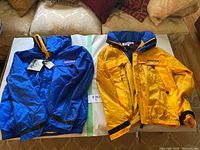 Blue and yellow Nautica jackets laid flat on surface showing fronts and colors