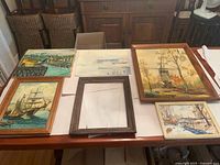 Six items laid on table: five Ray Marquis paintings in varied frames, one empty wood frame