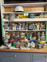 Full view of shelving with numerous containers of nails, screws, ropes, hard hat and knee pads