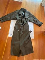 Full view of olive green trench coat laid flat