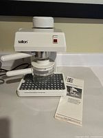 Front view of Salton espresso maker showing body, drip tray and manual