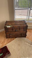 Front view of antique flat-top steamer trunk showing wood slats, metal bands, center lock and latches