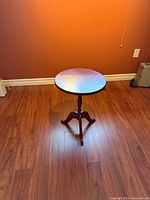 Round wooden pedestal side table on hardwood floor