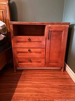 One of the wooden bedside tables showing open shelf, three drawers and cabinet door