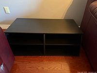 Front view of black shelving unit showing four open compartments