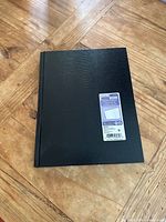 Front cover of black textured hardcover journal with retail sticker