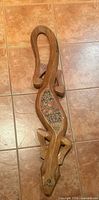 Full view of carved wooden lizard wall hanging on tiled floor