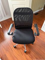 Front view of black mesh swivel office chair showing mesh back, cushioned seat, armrests, and five-star base with casters