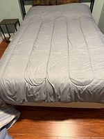 Double bed with grey bedding on metal frame, hardwood floor visible