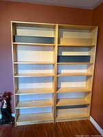 Two matching light wood Ikea bookcases side by side showing shelves and finish