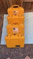 Four stacked yellow Pelican 1400 cases showing handles and exterior numbers