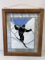 Front view of stained glass panel showing skier design and oak frame