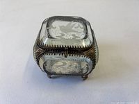 Full view of square faceted glass jewelry box showing brass frame and feet