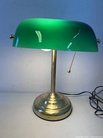 Lamp front view lit, showing green glass shade and brass base