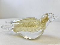 Left side view of clear art glass bird showing gold frit interior