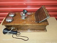 Top view of oak telephone lying flat showing twin nickel bells, transmitter, writing shelf, and handset