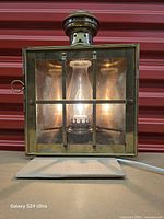 Front view showing brass body, grid, glass panels, and illuminated bulb