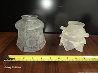 Two frosted glass lamp shades side by side with tape for width