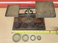 Top view of scale with pans, wooden base, recesses for weights and tape measure for dimensions